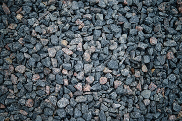 Dark gravel texture with small stones scattered in various shapes and sizes on the ground