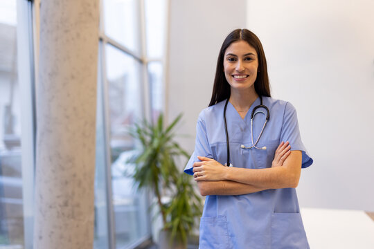 Confident female healthcare worker standing with crossed arms, radiating professional demeanor in contemporary medical environment