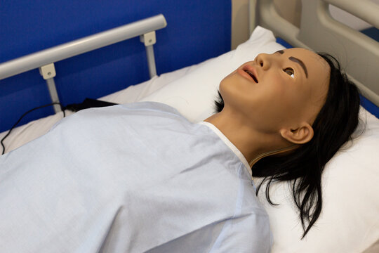 Realistic medical mannequin lying in hospital bed for healthcare training, clinical simulation and nursing practice. Used to teach patient assessment monitoring, airway skills. Emergency response
