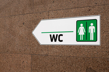 Sign directing to the WC with gender specific icons for men and women. The clear green and white...
