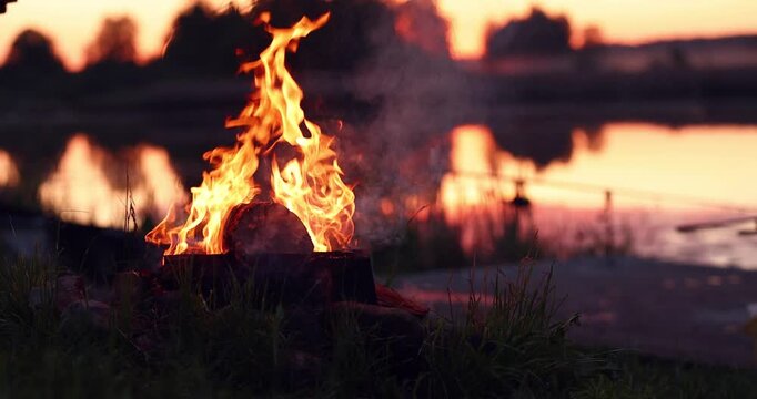 Bright flame burning near the river in the evening. Slow motion effect