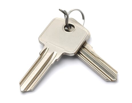 Two silver house keys on a white background