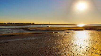Sunset at Mont Saint-Michel, Normandy, France – sunlight reflecting on wet tidal flats during low tide.
