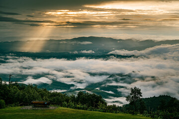 Sunlight breaks through the clouds, creating stunning rays of light that illuminate the scene. This scenic view captures the tranquil and mystical atmosphere of the highlands.