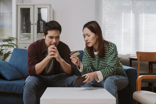 Young couple looking worried while checking their credit card and bank account balance on their smartphone, facing financial difficulties