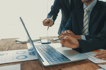 Business people reviewing financial reports on a laptop, pointing at the screen and discussing data...