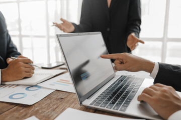 Business colleagues reviewing project progress and analyzing financial data on laptop during team...