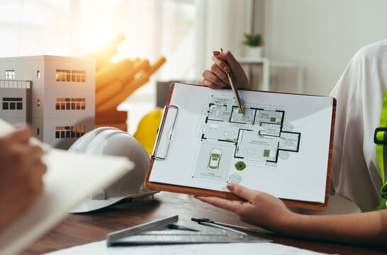 Architect presenting a detailed house plan to a client during a professional meeting, fostering collaboration and discussing design elements
