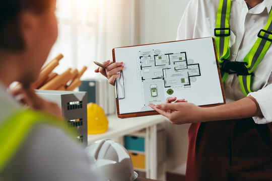 Two architects engaged in a discussion about a new project, analyzing house plans and collaborating on design ideas in the office