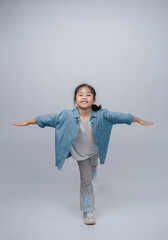 Young girl demonstrating balance and agility with arms outstretched in a playful pose against a...
