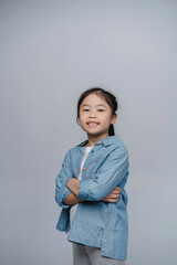 Young girl smiling confidently, wearing blue shirt and gray leggings, standing against plain...