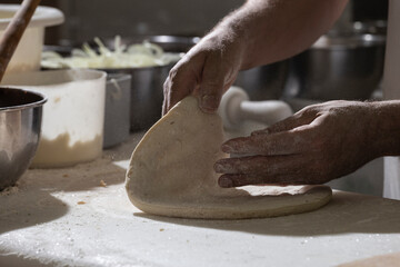 Chef pizzaiolo prepara uma pizza abrindo a massa com as mãos