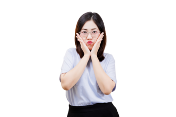 A young Asian young beautiful woman with glasses makes a funny face, placing her hands on her cheeks, conveying surprise or playfulness.
