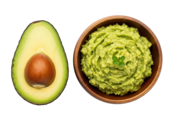 Overhead view of halved avocado and bowl of guacamole with garnish food green