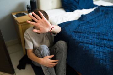 Obraz premium Teenager hiding face with hand in bedroom