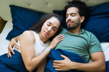Serene couple sleeping peacefully in bed, embracing comfort and love
