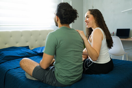 Loving couple relaxing and talking on bed in bedroom