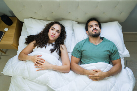 Young couple lying in bed having relationship problems - Powered by Adobe