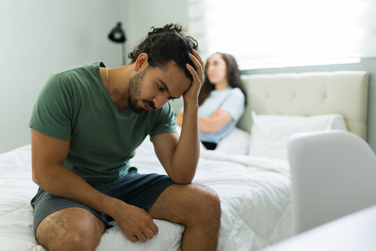Sad young man feeling depressed after arguing with partner in bedroom