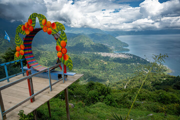 Colorful viewpoint with a fruit-decorated arch overlooking the scenic Lake Atitl&aacute;n in Guatemala, surrounded by mountains and lush forests.