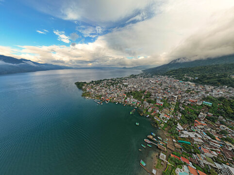 Aerial panoramic view of Lake Atitl&aacute;n and San Pedro in Guatemala with volcanic mountains, lush green landscape, and dramatic sky over Central America