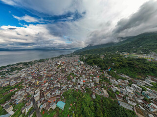 Aerial panoramic view of Lake Atitlán and San Pedro in Guatemala with volcanic mountains, lush...