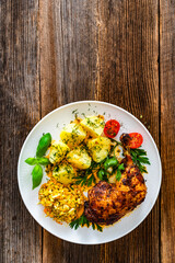 Oven roasted chicken leg with boiled potatoes and young cabbage salad on wooden table