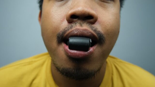 Close-up of a man with a jaw exerciser in his mouth, commonly used to tone facial muscles, define jawline, and improve appearance.
