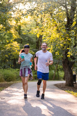 Obraz premium Happy diverse couple jogging outdoors in a park, smiling and enjoying an active lifestyle together on a sunny day
