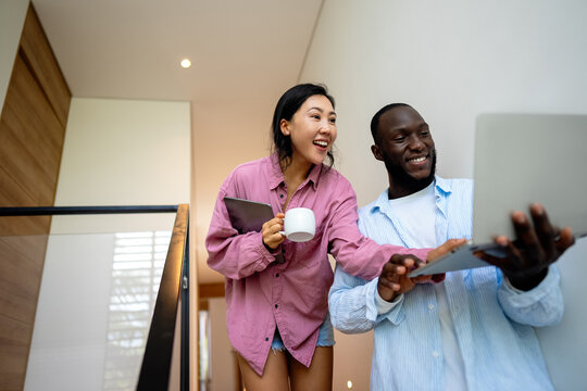 Happy multiethnic diverse couple, people using digital laptop for online shopping or payment. - Powered by Adobe