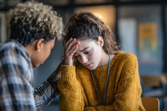 African female school psychologist supporting sad teenage girl during her difficult situation at school