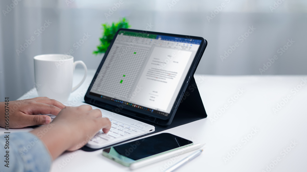 Aufkleber close up of hands typing on wireless keyboard connected to tablet showing spreadsheet and document, 