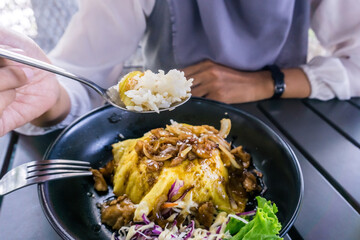 A woman enjoying a delectable chiffon egg chicken teriyaki meal with rice and a fresh side salad. Perfect for food, culinary, and lifestyle concepts