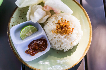 A delicious, complete meal of Minapadi chicken curry with rice, crackers, and chili sauce