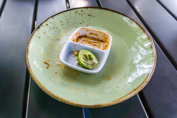 Empty plates and a small sauce dish with leftover lime and chili paste, remnants of a delicious meal