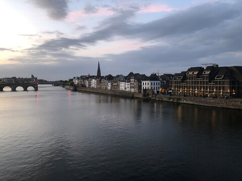 Eastern View of Maastricht with the Meuse and Historic Stone Bridge &ndash; Dutch Architecture, Calm River, and Clear Sky Reflect the Timeless Charm of Limburg&rsquo;s Capital in the Heart of the Netherlands