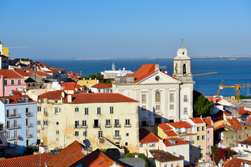 Fototapeta premium panoramic view of the Alfama district of Lisbon, Portugal, with the Igreja de Santo Estêvão (Church of St. Stephen) in the foreground and the Tagus River in the background