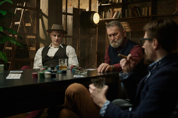 Three gentlemen playing poker game in a vintage old library