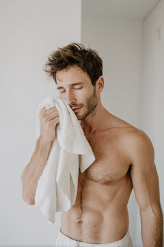 calm man wipes his face with towel exhaling deeply eyes closed relaxing after refreshing shower
