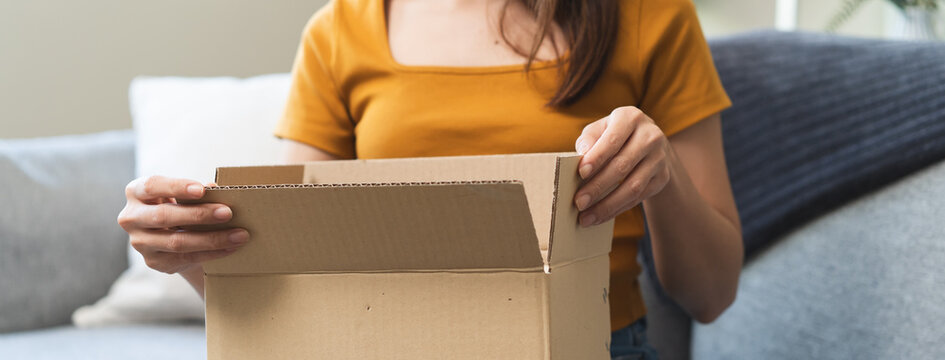 Close-up hands of Excited Young females opening box at home