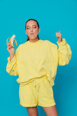 Woman in yellow clothes eating banana on blue background