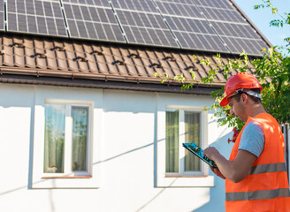 Engineer with Tablet Inspecting Solar Panels on Roof