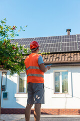 Engineer with Tablet Inspecting Solar Panels on Roof