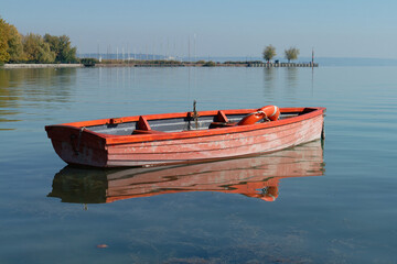 An orange wooden boat rests peacefully on the calm, blue water.