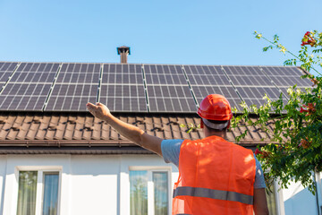 Engineer in Helmet Inspecting Solar Panels on Roof