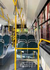 Interior of a bus. Modern bus interior with patterned seats and yellow handrails in bright daylight
