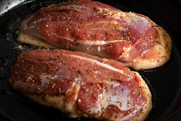 two duck breasts are fried in a pan, seasoned with salt and a mixture of peppers