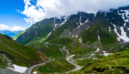 A winding mountain road snakes through a verdant valley, surrounded by snow-capped peaks.