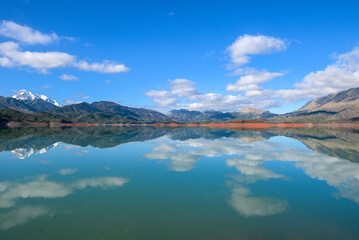 Beautiful landscape of lake and reflection of blue sky, clouds and mountains on surface of lake,...
