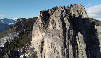 Majestic craggy peaks rise above a winter landscape, showcasing rugged rock formations against a clear sky.